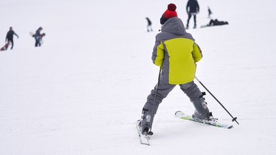 A teenage boy carefully skis down a snow-covered mountainside