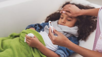 Ill child having her temperature taken by a woman