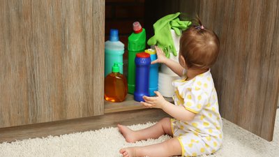 Little girl playing with detergents in kitchen