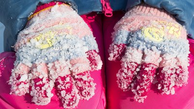 Lumps of frozen snow on woolen gloves