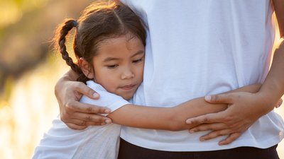 Sad asian child girl hugging her mother