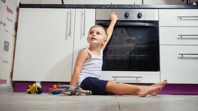 child playing in the kitchen with a gas stove