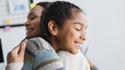 joyful african american woman and teenage girl embracing with closed eyes at home