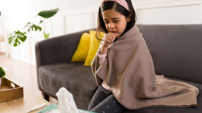 young girl on couch coughing