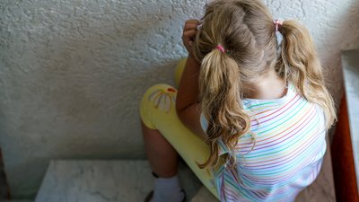 young girl with pigtails upset on staircase